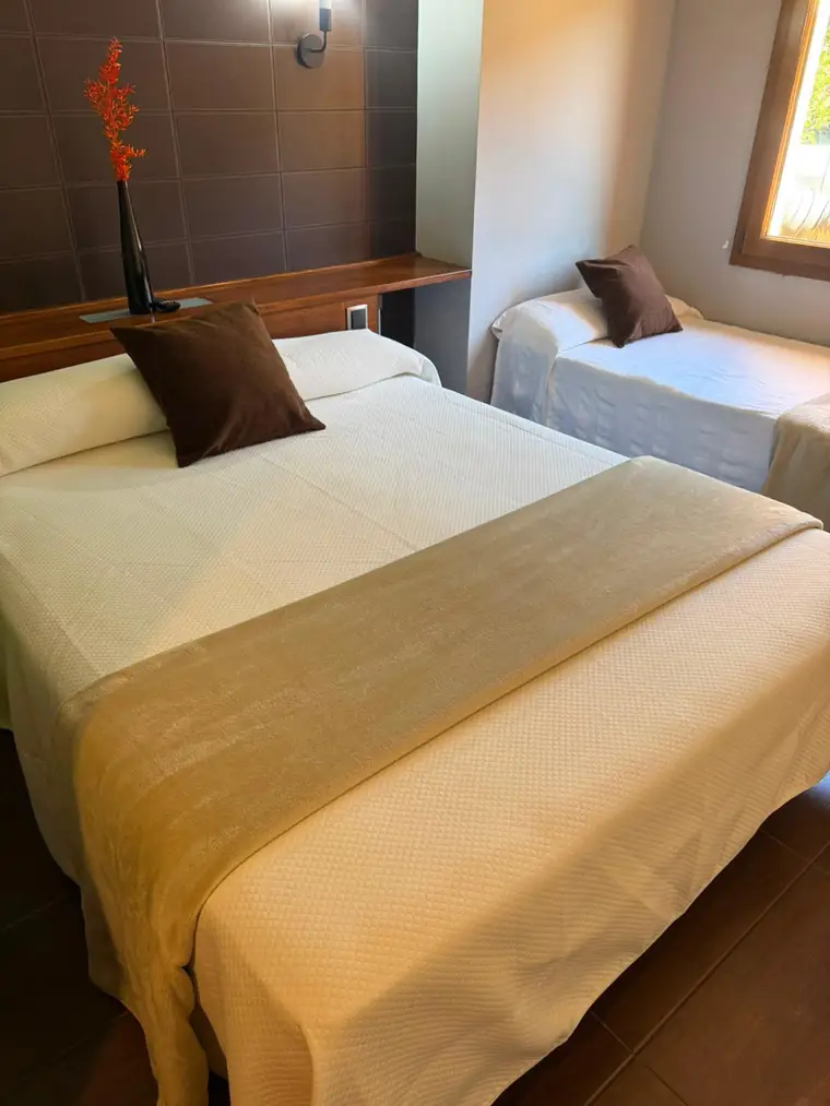 Habitación con una cama doble y una individual junto a la ventana