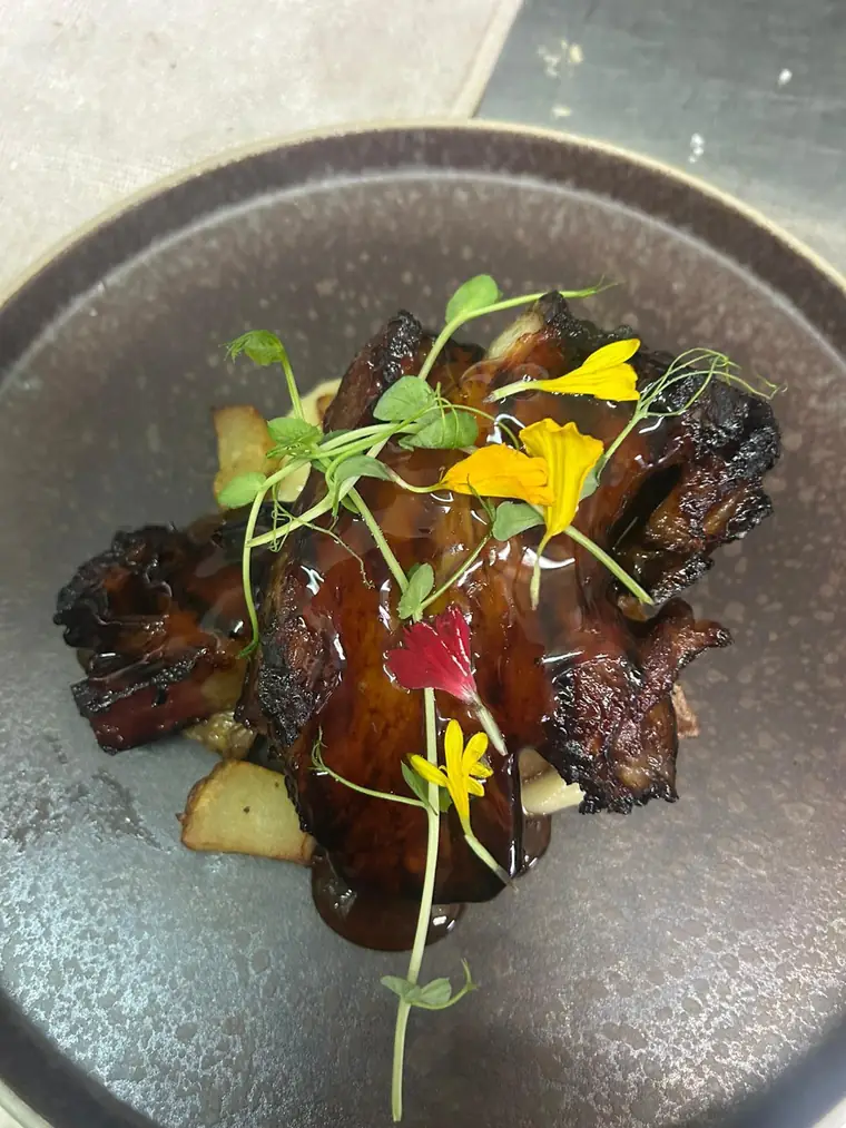 Carne con salsa, brotes y flores