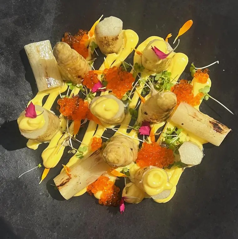 Plato de verduras con flores comestibles sobre pizarra