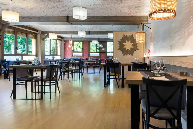 El comedor de la Fonda Farré, con mesas de madera y ventanas a los árboles